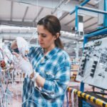 Professional young industrial factory woman employee working  with machine parts putting, checking and testing industrial equipments cables in large Electric electronics wire and cable manufacturing plant factory warehouse